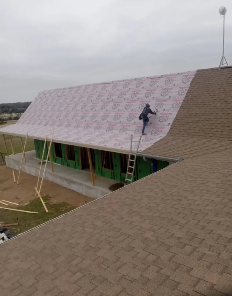 Worker preparing underlayment for a metal roof installation in Tega Cay